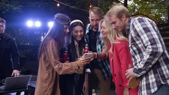 Young People Looking Photos on Their Female Mate's Smart and Having Fun Together in the Gazebo