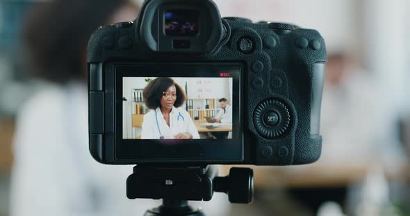 Female Doctor which Streaming Conversation from Medical Lab Near Hardworking on Laptop