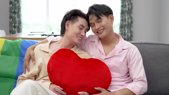  Portrait of Happy Asian gay couple embracing and showing their love with red heart pillows