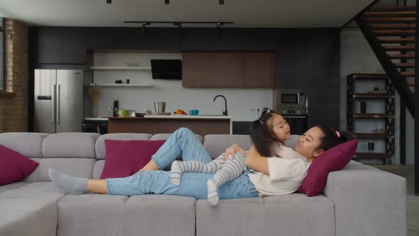 Cute Asian Toddler Girl and Mom Embracing on Couch