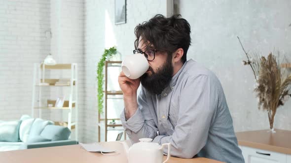 Handsome Bearded Man in the Kitchen Enjoy a Cup of Tea After a Hard Work Day