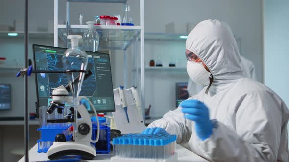 Chemist with Coverall Analysing Bacteria Sample From Petri Dish