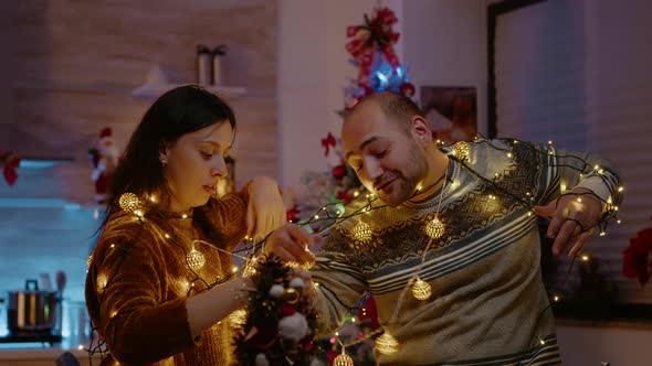 Festive Couple Knotted in String of Christmas Lights