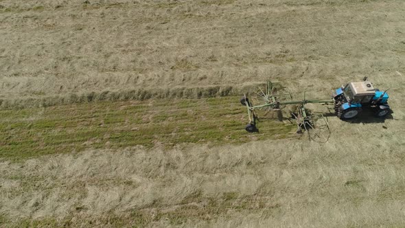 Tractor with Rake Tedders on the Farm Field