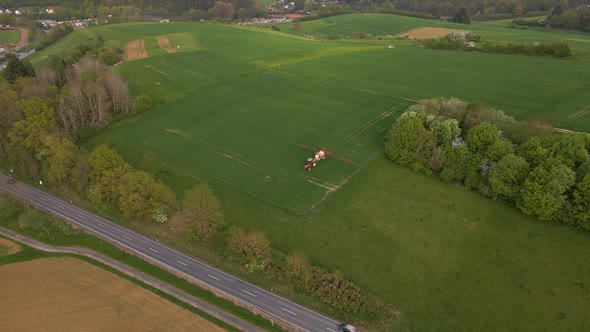 aerial footage of a large meadow in the german hesse region where a farmer is driving his tractor wi