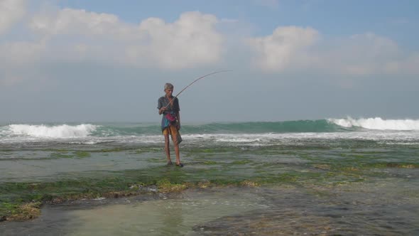 Fisherman Stands in Foaming Ocean at Green Seaweed Slow