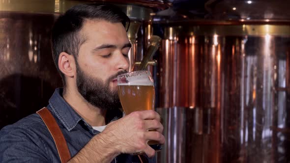 Handsome Bearded Brewer Enjoying Smell and Taste of Delicious Craft Beer