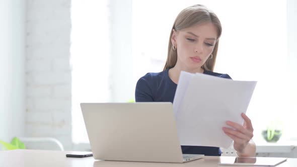 Woman with Laptop Reading Documents in Office