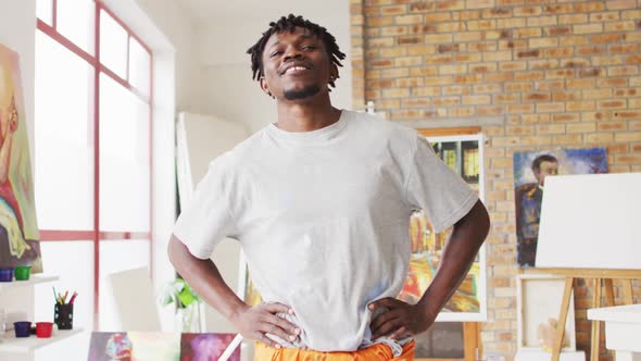 Portrait of african american male artist with hands on hips smiling at art studio