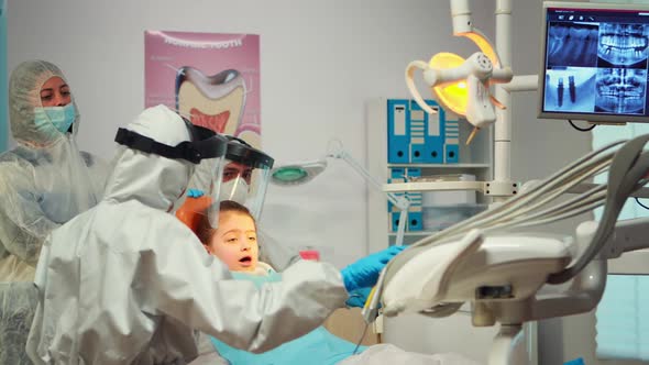 Little Girl Wearing Ppe Suit Looking in the Mirror After Dental Intervention