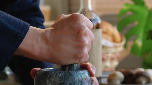 Hands of Man Grinding Spices with Mortar and Pestle