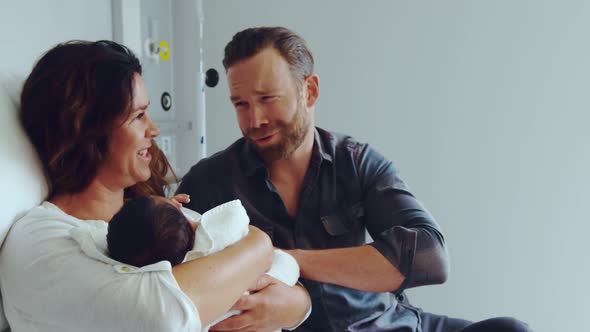 Front view of Caucasian couple holding their newborn baby in the ward at hospital