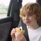 Blonde hungry boy eating a delicious cheeseburger in the car. - VideoHive Item for Sale