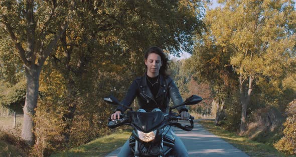 Beautiful european young lady riding her motorbike wearing leather jacket driving On road captured f