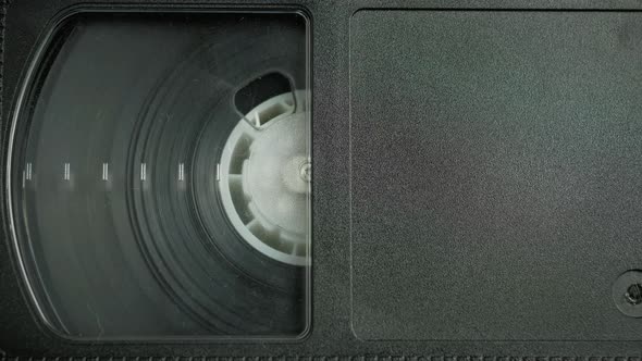 The Left Side of the VHS Cassette. a Film Reel Spins in a Small Cassette Window