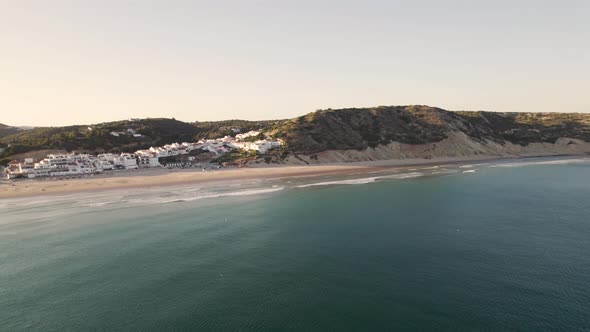 Aerial view of calming waves crashing at beautiful discreet beach Praia da Salema Algarve Portugal.