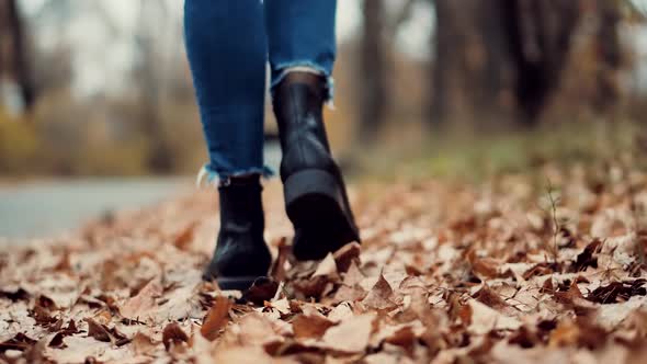 Woman Legs In Leather Shoes Walking On Vacation Holiday In Cold Autumn Day. Legs On Casual Sneakers.