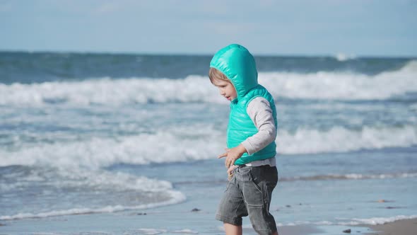 Toddler Boy in Waistcoat Is Playing with Sand on Sea Side.