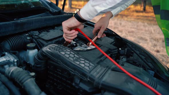 Close Up of a Man Charging Car Battery with Electricity Trough Jumper Cables