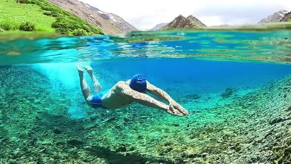 Young male Swims without a mask in a clear alpine lake