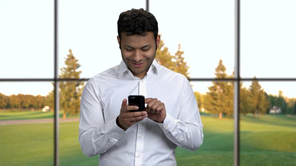 Young Handsome Businessman Using App on Smartphone.