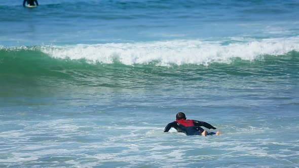 Male Trying to Swim on Surfing Board Through Waves in Ocean, Summer Active Sport