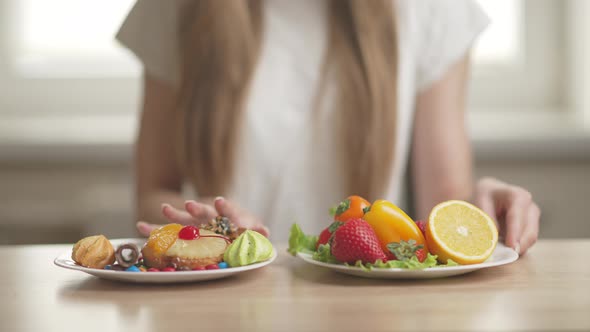 A Sporty Woman is Making Choice Between Fresh Fruits and Crisps