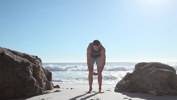 Young man doing yoga on beach