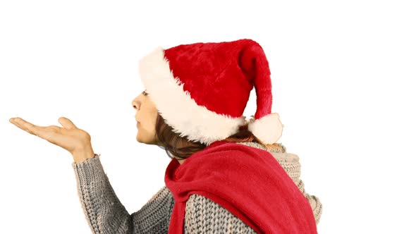 Girl in santa hat and warm clothing blowing over hands