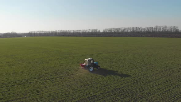 Tractor Spreading Artificial Fertilizers in Green Field. Farmer Fertilizing Arable Land with