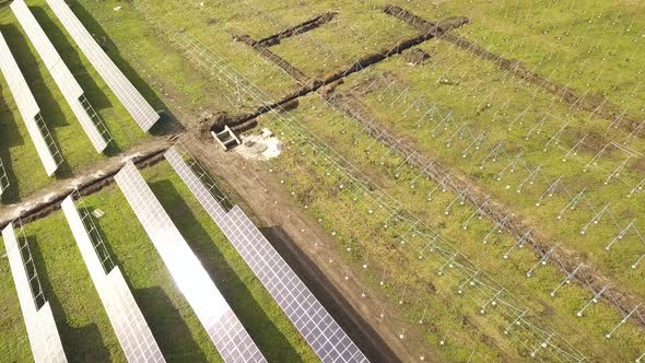 Aerial view of solar power plant under construction on green field. Assembling of electric