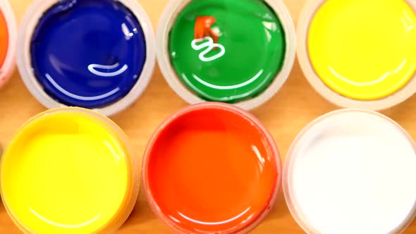 Varicolored Gouache Jars on Wooden Background