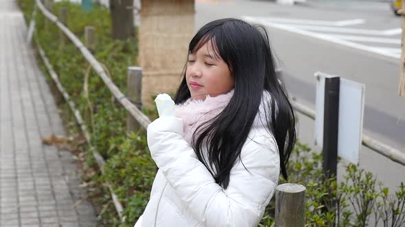 Little Asian Girl Smiling  And Eating Ice Cream Outdoor 