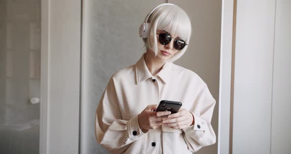 Beautiful Woman with White Hair Using Mobile Phone with Wireless Headphones