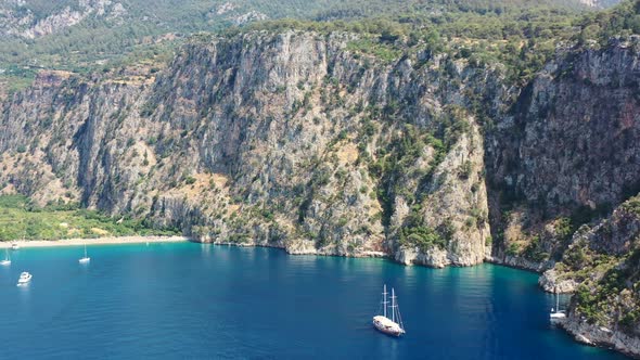 aerial drone panning up towards the large green mountains of Butterfly Valley while boats are anchor