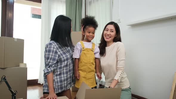 LGBT Family Unpacking Boxes In New Home On Moving Day.