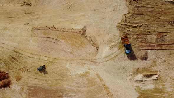 Aerial view movement of roller tractor and dump truck unload sand