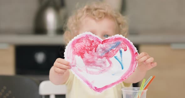 Close Up of a a Red Heart Cutted and Drawed By the Little Girl with Watercolors Presenting It to