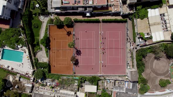 Three tennis courts next to each other with people playing tennis; aerial