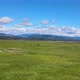 Perfect marsh, wavy windy green grass in marshland, distant snowcap mountain hills, clouds, blue sky - VideoHive Item for Sale