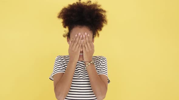 Funny Young Woman Laughing While Covering Face with Hands on Yellow Background