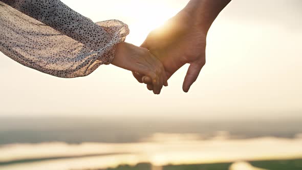 Young Couple of Man and Woman Taking Each Other By the Hand on Sunset