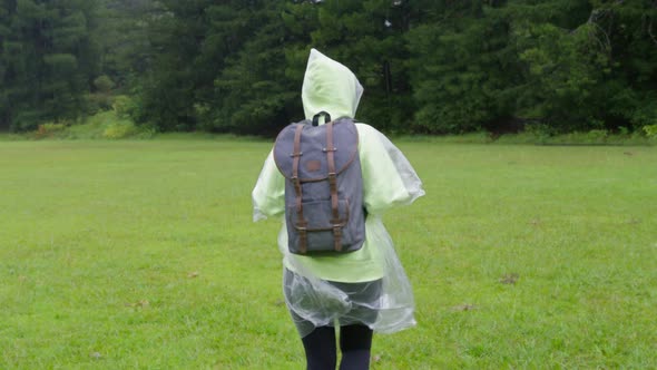 Tourist in Rain Poncho Exploring Rainforest with Cinematic Meadow at Rain