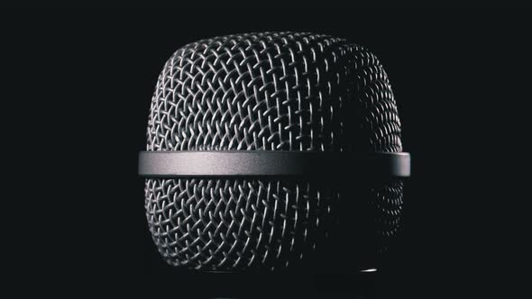 The Microphone Rotates on a Black Background. Dynamic Microphone Grid Spins Close-up