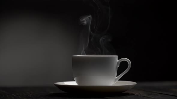 Steam Slowly Rising From a Cup of Hot Coffe. Dark Background