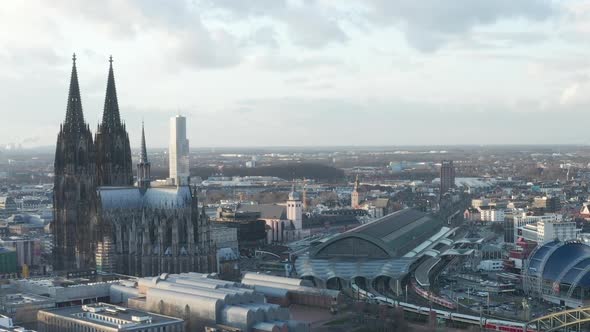 AERIAL: Circling Around Beautiful Cologne Cathedral with Central Train Station in Beautiful Hazy