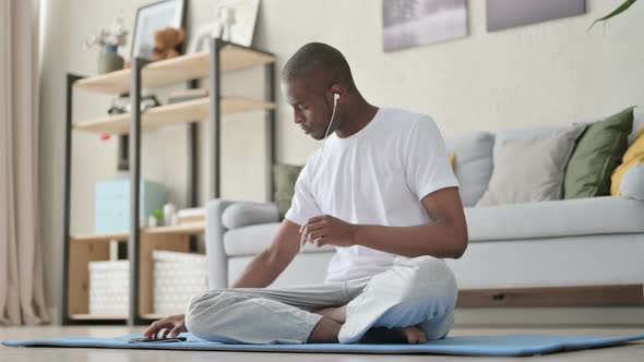 African Man Listening Music on Headphones and Meditating