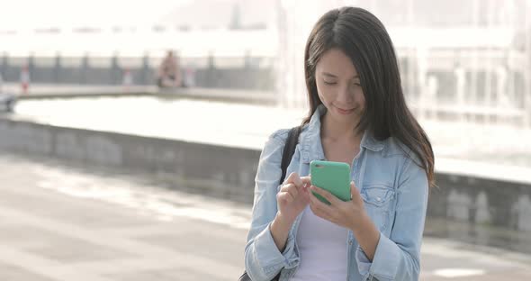 Woman working on mobile phone at street