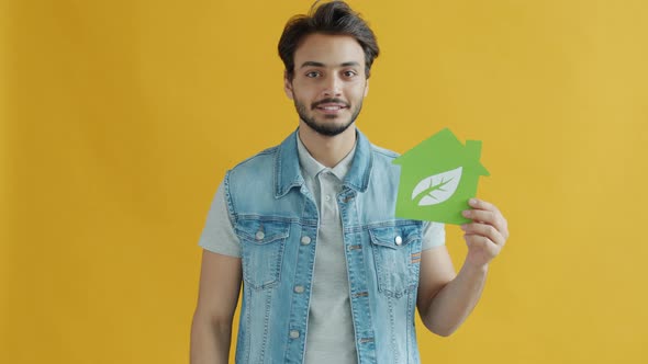 Slow Motion of Arab Brunet Pointing at Green Energy Symbol and Smiling on Yellow Background