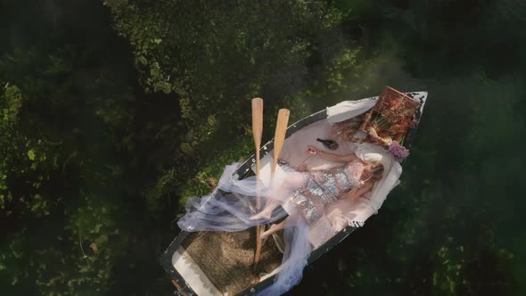 Fashion woman laying in rowing boat putting on sunglasses and drinking champagne on a luxury rowing 